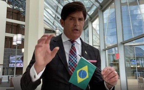 Imagem de Dr. Robert Rey em um hospital norte-americano segurando uma bandeira do Brasil