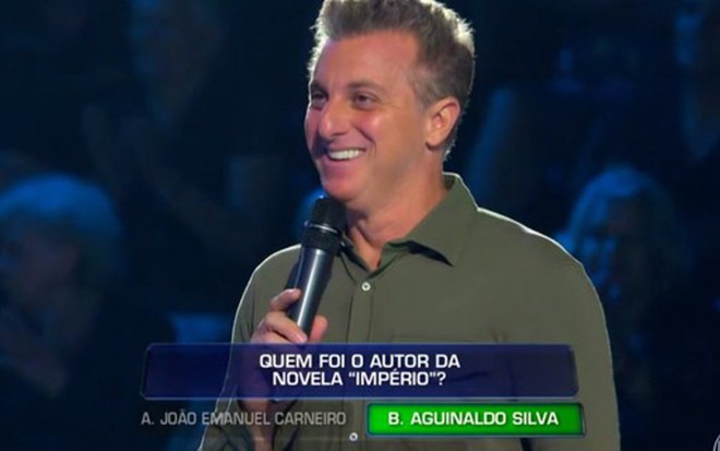 Luciano Huck sorri ao apresentar o quadro The Wall