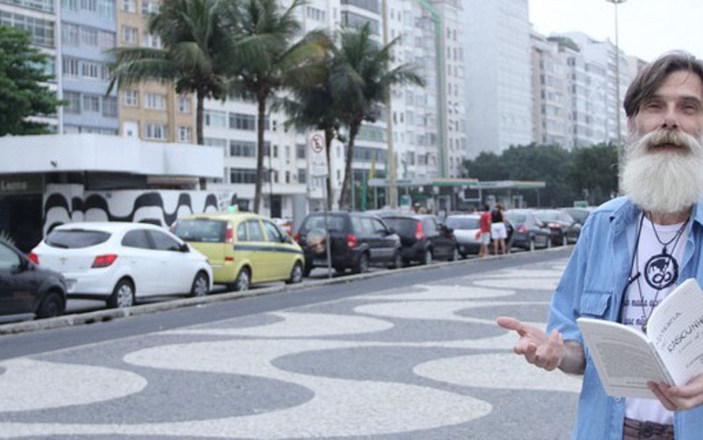 Eduardo Tornaghi exibe livro que vende nas ruas no calçadão da praia do Leme, no Rio - Rodrigo Anjos/Notícias da TV