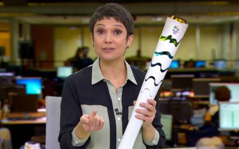 A jornalista Sandra Annenberg exibe sua réplica da tocha olímpica na bancada do Jornal Hoje - Reprodução/Globo