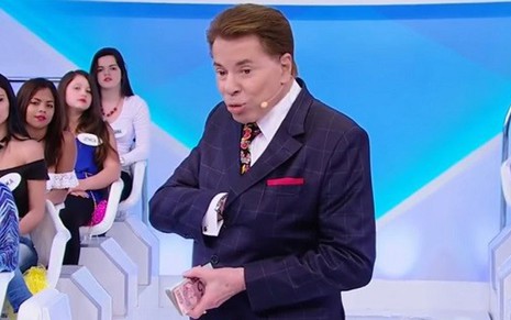 Silvio Santos junta dinheiro antes de jogá-lo para a plateia em programa de outubro de 2015 - Reprodução/SBT