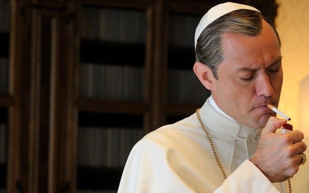 O papa vivido por Jude Law não larga o cigarro nem na reza em The Young Pope, da HBO - Divulgação/HBO