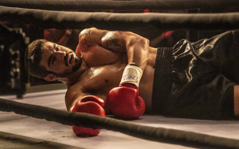 O ator Caio Castro em cena como Rock, caído num ringue durante luta em A Dona do Pedaço