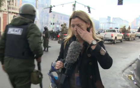 A repórter Teresa Bo durante transmissão ao vivo para a TV Al Jazeera enxuga os olhos após ser atingida com spray de pimenta em um protesto na Bolívia 