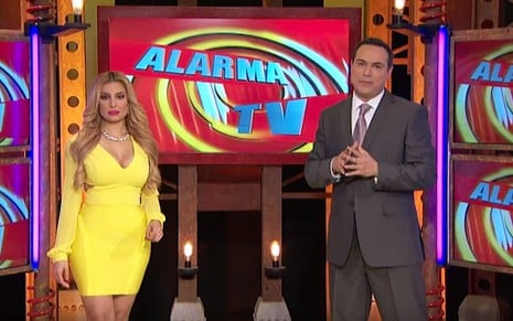Com um vestido amarelo, Janice Villagrán apresenta o telejornal Alarma TV ao lado de Sergio Catalán, de terno