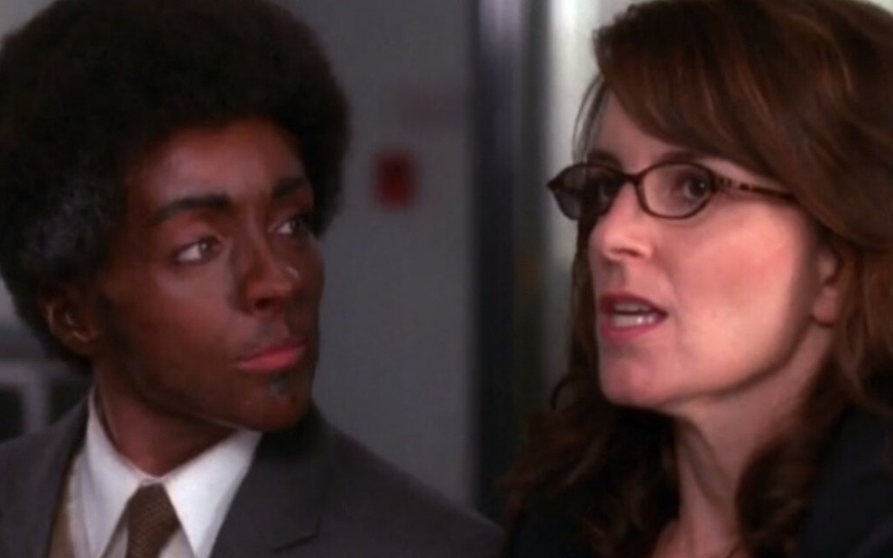 Com peruca black e cara pintada de preto, Jane Krakowski olha para Tina Fey em episódio da comédia 30 Rock