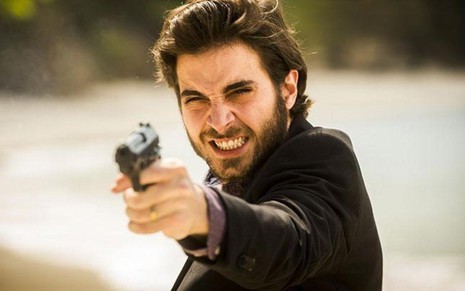 O ator Fiuk com revólver apontado e expressão de sofrimento em cena de A Força do Querer