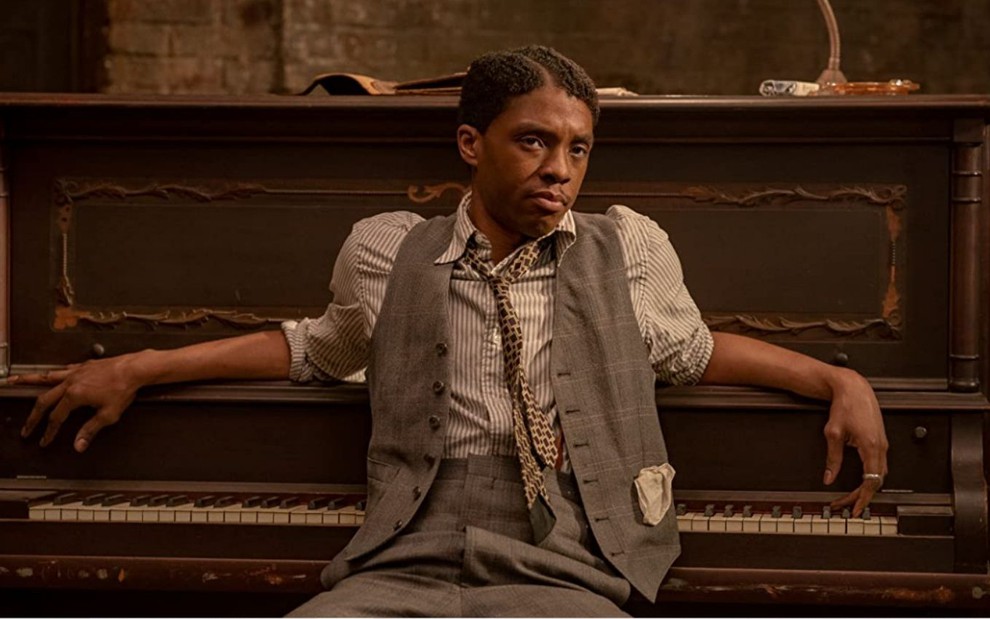 Chadwick Boseman sentado em frente a um piano em cena do filme A Voz Suprema do Blues (2020)