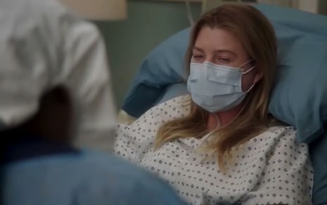 Com máscara e deitada em uma cama de hospital, Ellen Pompeo está triste como Meredith em Grey's Anatomy