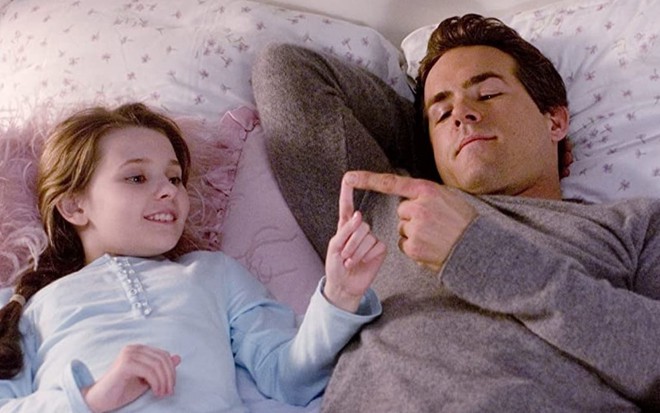 Abigail Breslin e Ryan Reynolds estão deitados em uma cama conversando em cena do filme Três Vezes Amor (2008)