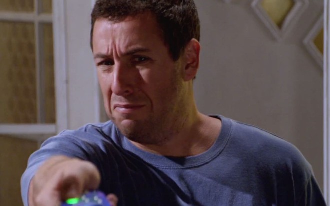 Adam Sandler olha para frente e aponta com o controle remoto em cena de Click (2006)