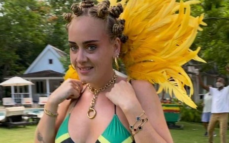 Imagem de Adele usando um biquíni com a bandeira da Jamaica, tranças e penas amarelas 