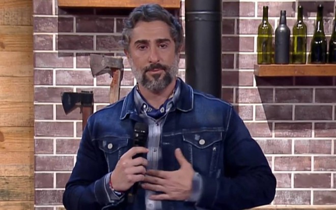 Marcos Mion encara a câmera, bastante emocionado e segura o microfone nos bastidores do programa A Fazenda 12