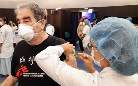 Otávio Augusto recebe vacina contra Covid-19 de enfermeira paramentada com uniforme