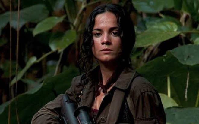 No meio de uma mata, Alice Braga segura uma arma de fogo em cena do filme Predadores (2010)