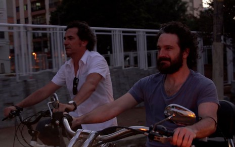 Eric Belhassen e Caco Ciocler andam de moto em cena do filme AmarAção