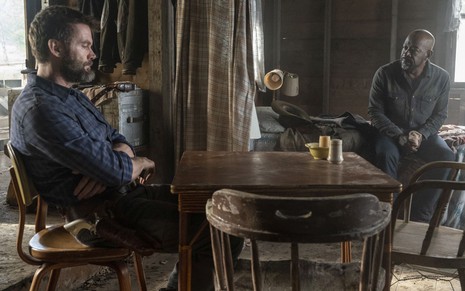 Garret Dillahunt e Lennie James estão sentados em um ambiente similar a um bar de faroeste em cena de Fear the Walking Dead