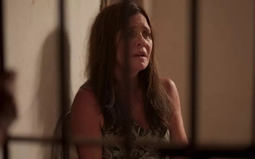 A atriz Adriana Esteves com expressão de sofrimento no cenário do cativeiro de Lurdes em Amor de Mãe