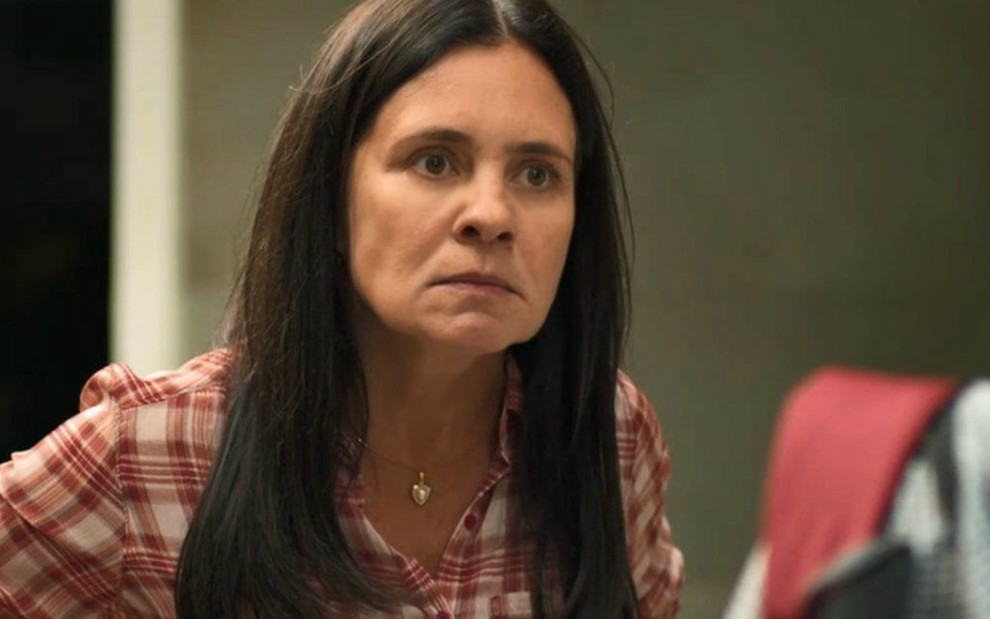 A atriz Adriana Esteves faz cara de brava em cena da novela Amor de Mãe na qual usa uma camisa xadrez