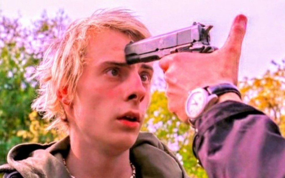 Calin Stanciu Jr., como Alex, em Anaconda 4 - Rastro de Sangue; ator está com uma arma apontada na cabeça