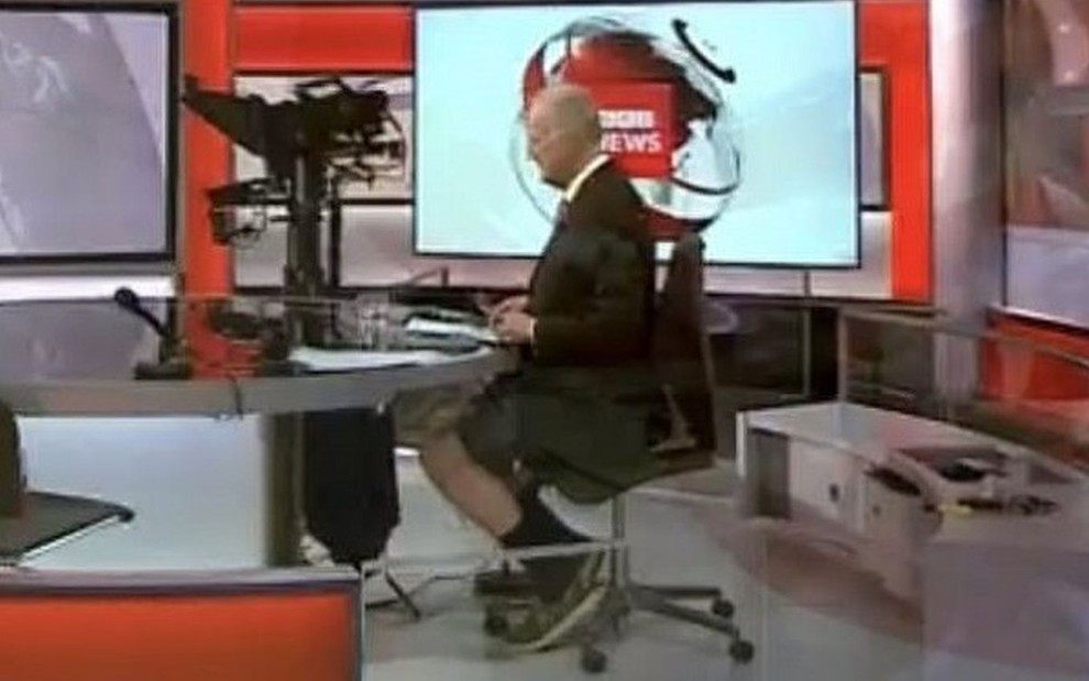 Shaun Ley de terno e bermuda atrás da bancada do jornal BBC News