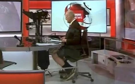 Shaun Ley de terno e bermuda atrás da bancada do jornal BBC News