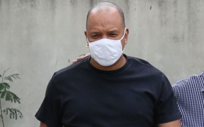 Vocalista do grupo Molejo, Anderson Leonardo, de camiseta preta e máscara branca, acompanhado de funcionários da 33ª DP