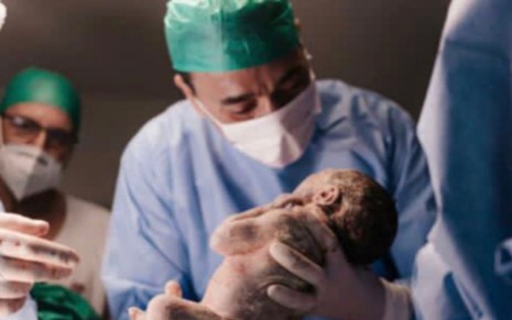 André Rizek segura seu filho recém-nascido em foto do dia do parto de Andréia Sadi