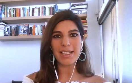 Andréia Sadi de cropped branco, brincos de argola, em escritório de sua casa
