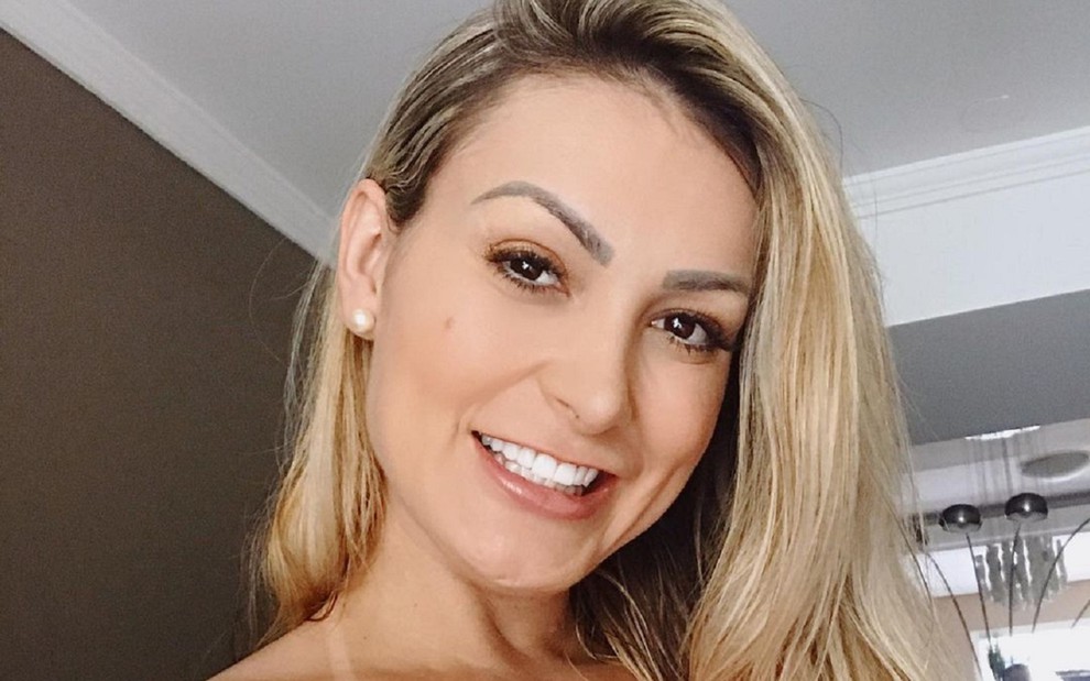 Andressa Urach em foto do Instagram olhando e sorrindo para a câmera com um vestido laranja