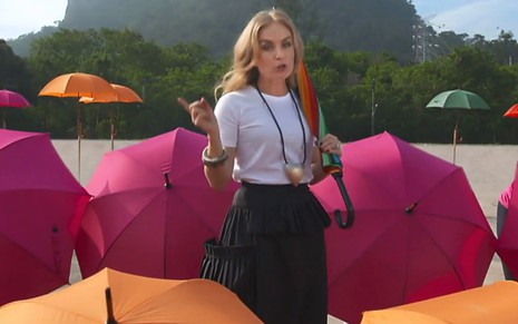 A apresentadora Angélica andando à frente de guarda-chuvas coloridos durante gravação de seu novo programa