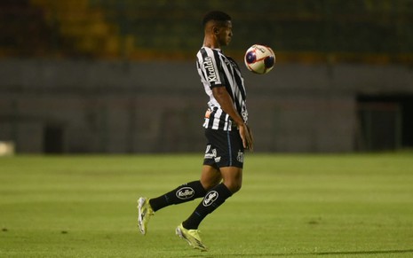 O jogador do Santos Ângelo em lance no campo vestido com o uniforme do time nas cores preto e branco