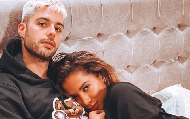 Gui Araújo e Anitta deitados e abraçados na cama de casal