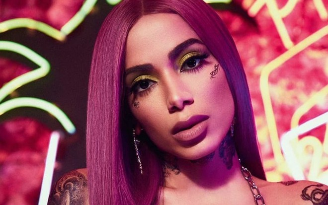 Imagem de Anitta com cabelo roxo e corpo com tatuagens em ensaio fotográfico