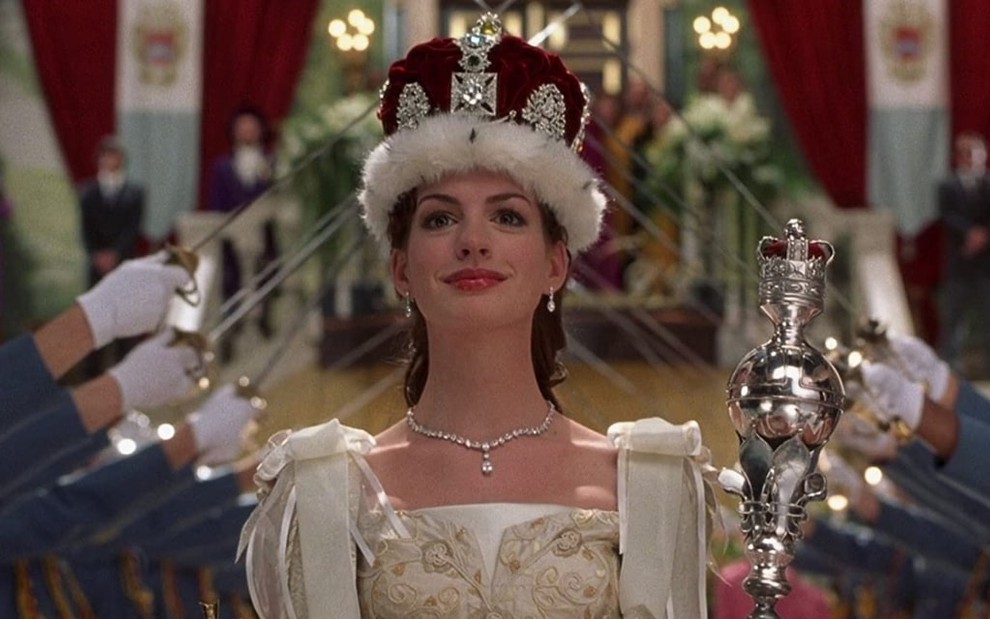 Anne Hathaway usa uma coroa grande em vermelha em cena como Mia Thermopolis de O Diário da Princesa 2