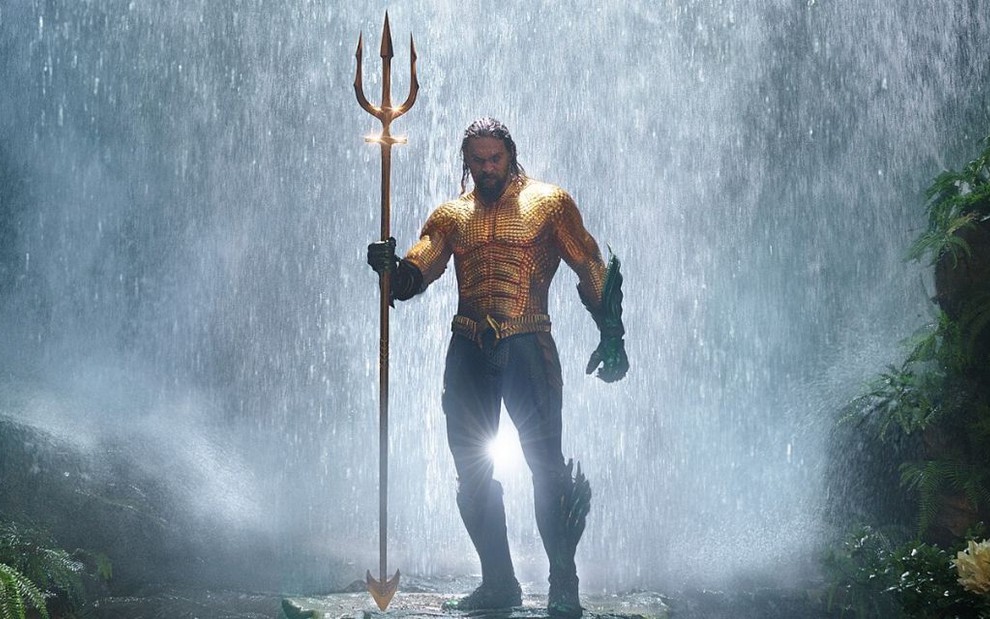Ator Jason Momoa, no papel de Aquaman, segurando um tridente dourado em uniforme do herói