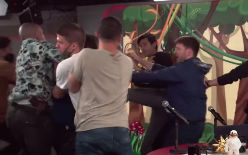 Pessoas tentam separar Tomé Abduch de André Marinho durante briga no estúdio do Pânico; entre elas, um segurança armado