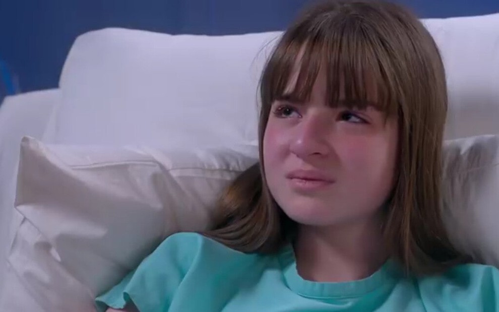 Protagonista de Poliana, Sophia Valverde chora na cama de um hospital em cena da novela do SBT