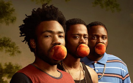 Os três atores principais de Atlanta estão alinhados em pé, cada um com uma bola na boca. Da esquerda para a direita, Donald Glover veste camiseta vermelha,  Lakeith Stanfield está de regata e Brian Tyree Henry usa uma camisa polo com listras horizontais