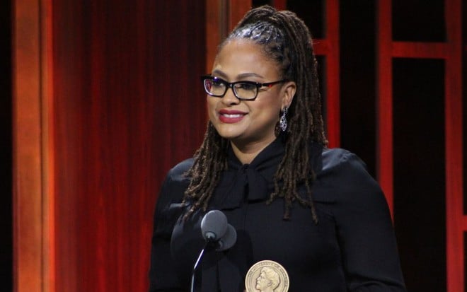 Ava DuVernay sorri em púlpito ao receber troféu na cerimônia Peabody Awards