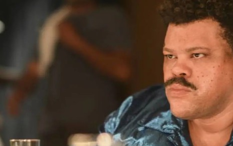 Babu Santana, caracterizado como o cantor Tim Maia, olha para espelho em cena do filme homônimo