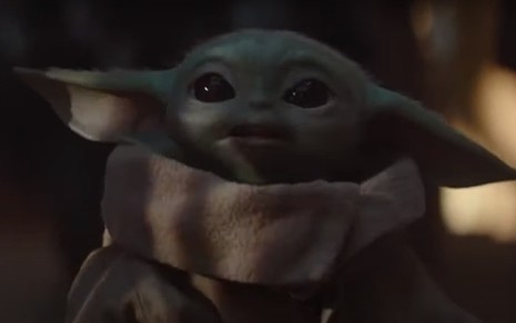 Personagem Baby Yoda caminhando em meio a floresta em cena da série The Mandalorian do Disney+