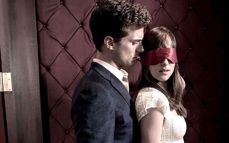 Christian Grey (Jamie Dornan) encostado em Anastasia Steele (Dakota Johnson), de olhos vendados, em Cinquenta Tons Mais Escuros