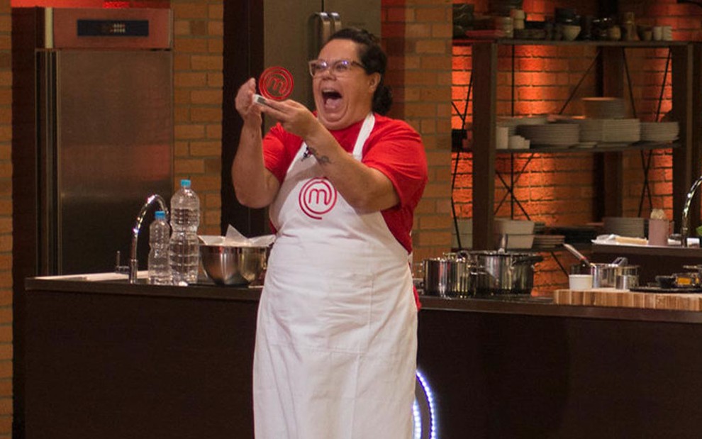 Gritando de alegria, a cozinheira Alessandra Maia ergue o trofeú de vencedora do terceiro episódio da sétima temporada do MasterChef