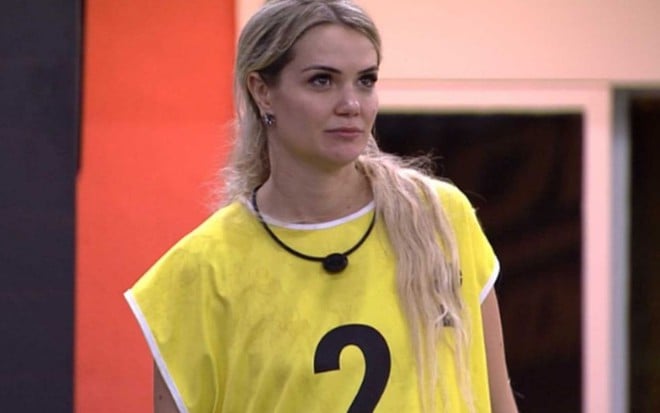 Imagem de Marcela Mc Gowan de colete amarelo com expressão de tristeza ao ouvir que estava fora da competição