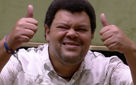 Babu Santana no Big Brother Brasil 20, ator sorri para a câmera e faz dois joínhas com as mãos