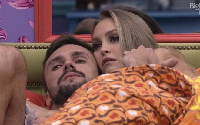 Imagem de Arthur Picoli (à esq.) e Carla Diaz deitado na cama de casal do quarto colorido no BBB21