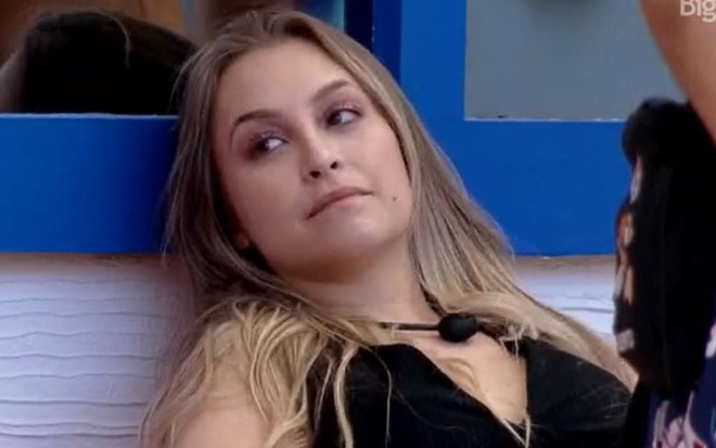 Carla Diaz olha para Sarah enquanto está sentada no sofá da área externa do BBB21