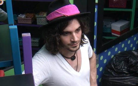 Fiuk olha para frente, usa camiseta branca, chapéu preto com lenço rosa