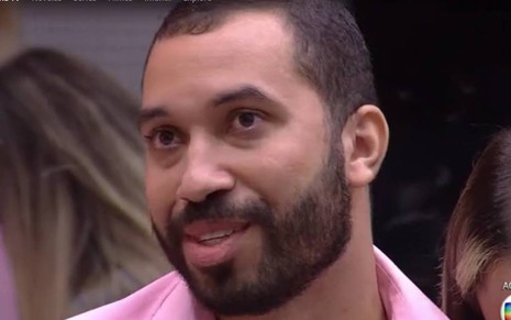 Gilberto Nogueira olha para o lado, sorri e usa camiseta rosa